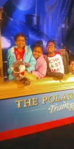 Cardinal Glennon kid Faith posing with sisters at Polar Express