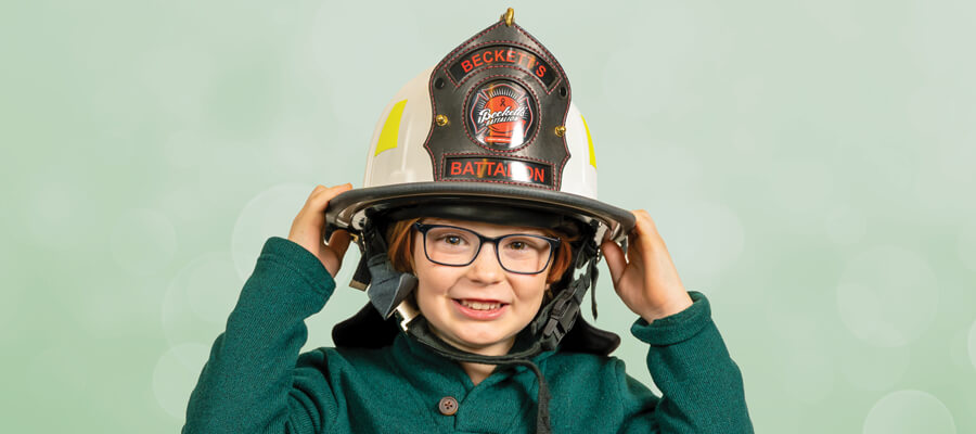 Beckett wearing his fireman hat in a green sweater