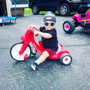 Easton riding tricycle with sun glasses and hat