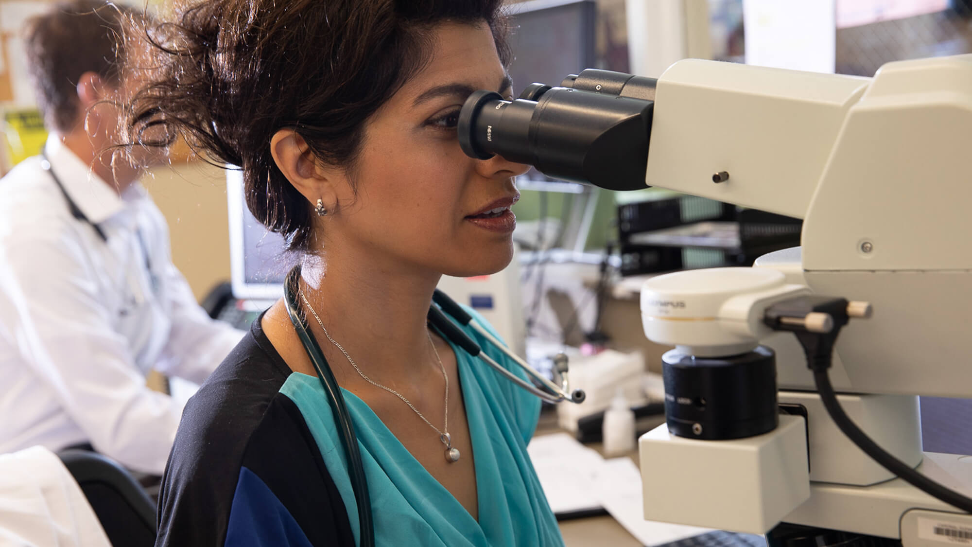 Physician looking into microscope in the hematology/oncology lab