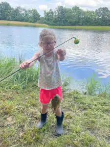 Kenzie - holding up caught fish on pole with lake in background