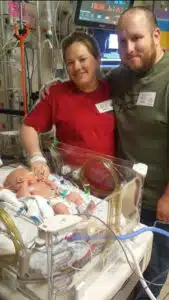 Kenzie - in NICU bed with mom and dad posing in background