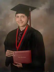 Logan - graduation portrait in cap and gown holding high school diploma