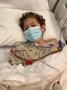 Logan - laying in hospital bed receiving treatment, wearing medical mask