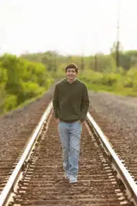 Logan - senior photo walking on train tracks
