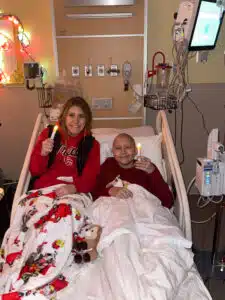 Logan - in hospital bed with sister, holding battery-operated candles at Christmas time