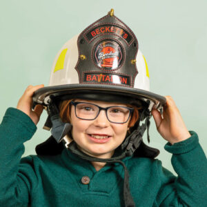 Beckett wearing his fireman hat in a green sweater