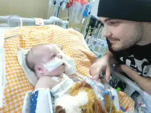 Easton - laying in PICU bed, he and dad looking at each other up close