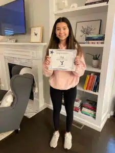 Olive - holding dance team certificate at home