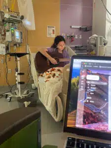 Olive - playing guitar in hospital bed at Cardinal Glennon