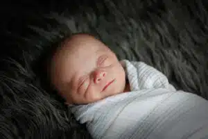 Colten newborn portrait - sleeping, swaddled on furry pillow