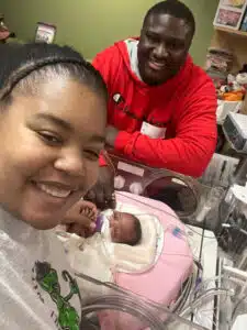 Jadai - mom selfie with Jadai in NICU bed and dad in background