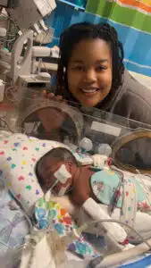 Jadai - sleeping in Giraf bed with mom posing behind in NICU room