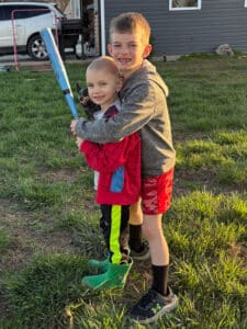 Wyatt and his brother posing with a baseball bat outside