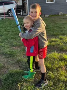 Wyatt and his brother posing with a baseball bat outside