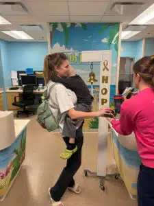 Wyatt held by his mom by the "Last Chemo" bell at Cardinal Glennon