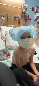 Wyatt wearing a mask and hair net in his hospital bed