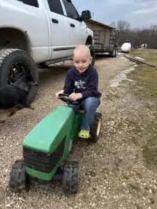 Wyatt riding a pedal tractor toy on the family farm