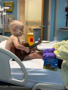 Wyatt playing a ukulele in his hospital bed