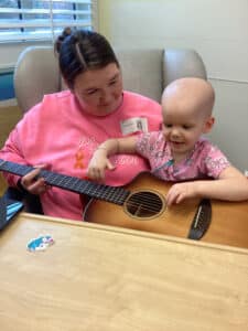 Cardinal Glennon patient Bristol and her mom in the Costas Center holding a guitar