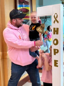 Cardinal Glennon patient Bristol being held by her dad and ringing the "Last Chemo" bell