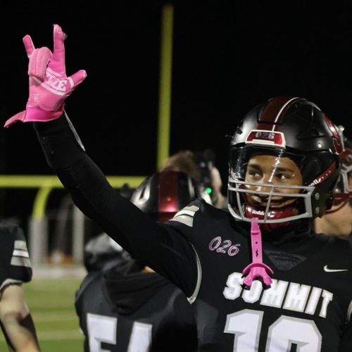Quincy holding up "I Love You" sign on hand during a football game on field