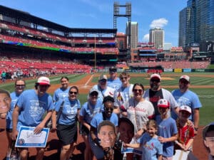 "Transplant Warrior" group photo on the field at Busch Stadium holding fatheads and signs for Quincy
