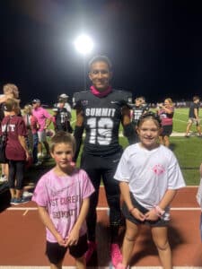 Quincy posing with younger siblings after a football game on the field