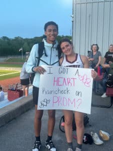 Quincy and his girlfriend holding a sign that says "I got a heart. Raincheck on Prom?"