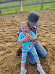 photo of a little girl being held by an older sibling and smiling