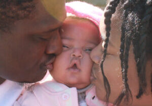 Jadai - close-up with mom and dad kissing her cheeks