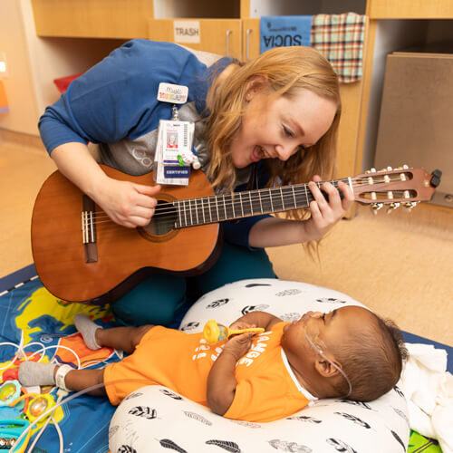 Music Therapist, Kimberly with patient Messiah in the NICU