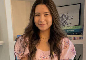 Olive - smiling at home in front of bookshelf