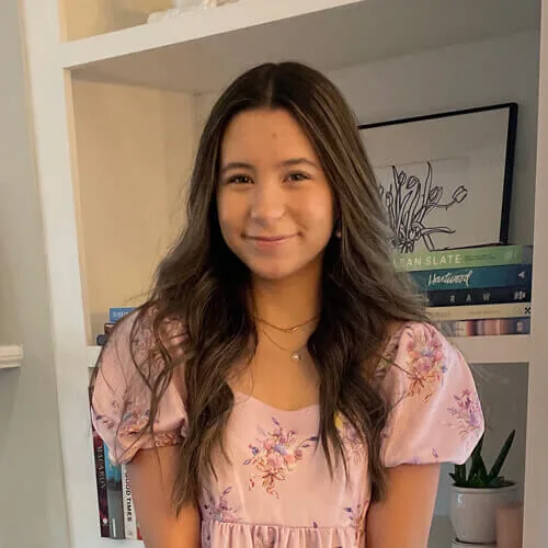 Olive - smiling at home in front of bookshelf