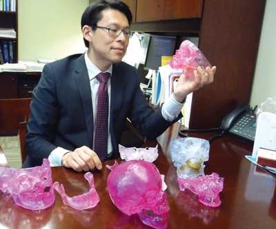 Dr. Alexander Lin holding a 3D craniofacial model.